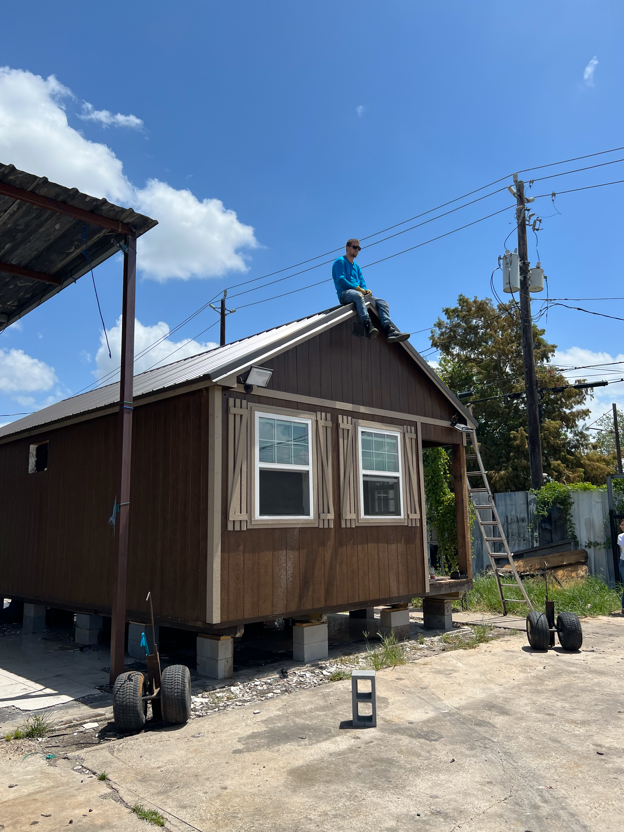 Crew member sitting on the roof of a home they are leveling